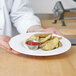 A chef holding a plate of potato wedges and ketchup.