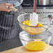 A person using a Vollrath medium mesh strainer with a wood handle to strain eggs.