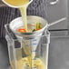A person pouring liquid into a container using a Vollrath aluminum fine china cap strainer.