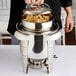 A person holding a Vollrath stainless steel food pan filled with pasta.