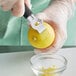 A person in gloves using a Mercer Culinary zester/channel knife to peel a lemon.