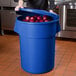 A woman opening a blue 55 gallon ingredient storage bin to reveal red onions.