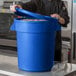 A man in a black coat opening a blue container with food.