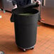 A woman holding a large black Mobile Ingredient Storage Bin filled with green beans.