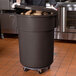 A man holding a brown mobile ingredient storage bin full of potatoes.