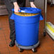 A woman in a blue room holding a blue mobile ingredient storage bin full of pasta.