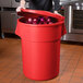 A woman holding a red round ingredient storage bin full of onions.