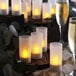 A group of Acopa flameless tea light candles in frosted plastic cups on a table