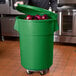 A man holding a green 55 gallon mobile ingredient storage bin full of onions.