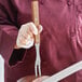 A person holding a Mercer Culinary Praxis® carving / pot fork over meat.