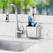 An OXO stainless steel sink caddy on a sink counter.