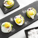 Three black plates with fried eggs sprinkled with Sabatino Tartufi Truffle Sea Salt on them.