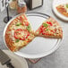 A slice of pizza with tomatoes and basil on a Choice aluminum pizza pan.