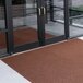 A brown Cactus Mat unbacked scraper mat in front of a glass door.