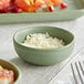 An Acopa sage ramekin filled with white food on a table.