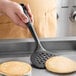 A person using a black OXO Good Grips nylon perforated spatula to lift pancakes.
