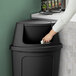 A woman using a Lavex corner round trash can lid to throw away a tissue.