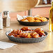 A Tablecraft gunmetal plastic diner platter used as a food basket on a table with a croissant inside.