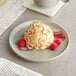 A dessert with raspberries on an Acopa Pangea Ash Matte Coupe Porcelain plate.