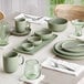 A sage green Acopa Pangea nappie bowl on a table with a spoon.