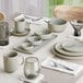 A table set with Acopa Pangea white porcelain plates and cups on a table.