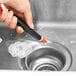 A hand using an OXO Good Grips brush to clean a sink.