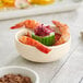 A bowl of shrimp and cucumber in an Acopa fog white ramekin on a table.