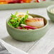 An Acopa Pangea ramekin filled with scallops, lemons, and greens on a table.