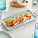 A rectangular Acopa Pangea porcelain platter with tomatoes on a table.