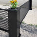 A black fence with a SelectSpace planter with a plant in it.