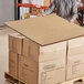 A man holding a large Lavex honeycomb cardboard panel box on a pallet.