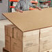 A person holding a Lavex Honeycomb Corrugate Panel box.