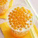 A cup of orange bubble tea with milk and orange Fanale Passion Fruit Popping Boba.