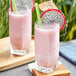 Two glasses of pink smoothie made with Fanale Dragon Fruit Concentrated Syrup with fruit slices and straws.