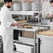 A chef using a Regency expeditor table to plate food.