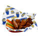 A red basket lined with a white customizable deli wrap featuring blue and yellow graphics, holding chicken wings and vegetable sticks.