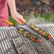 A person using Mr. Bar-B-Q non-stick kabob baskets to cook vegetables on a grill.