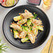 A table set with a plate of dumplings on an Acopa Izumi matte black melamine plate.