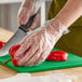 A hand in an AeroGlove cutting a red pepper.