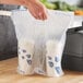 A hand holding a plastic bag with two Fast Take beverage carriers inside.