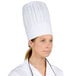 A woman wearing a white Chef Revival European chef hat.