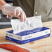 A person in gloves using Choice interfolded deli wrap to hold pepperoni.