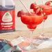Two glasses of red Jarritos slushies with straws on a table.