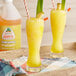 A pair of glasses filled with yellow Jarritos Pineapple slushy on a tray.