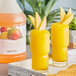 Two glasses of yellow Narvon mango slushies with fruit on the rim.