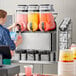 A woman pouring Carnival King cotton candy slushy concentrate into a container.