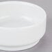 An Arcoroc white porcelain bowl on a gray surface.