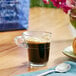 A glass cup of Lavazza Super Crema espresso on a table with a spoon.