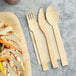 A HAY! cutlery pack with a wooden fork and spoon on a white surface.