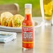 A case of Marie Sharp's Beware Comatose Habanero Hot Sauce on a table with tacos.